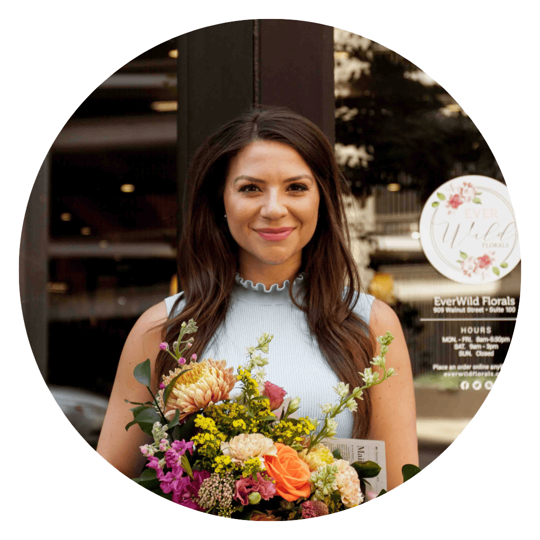 Woman holding a colorful flower bouquet outside EverWild Florals.